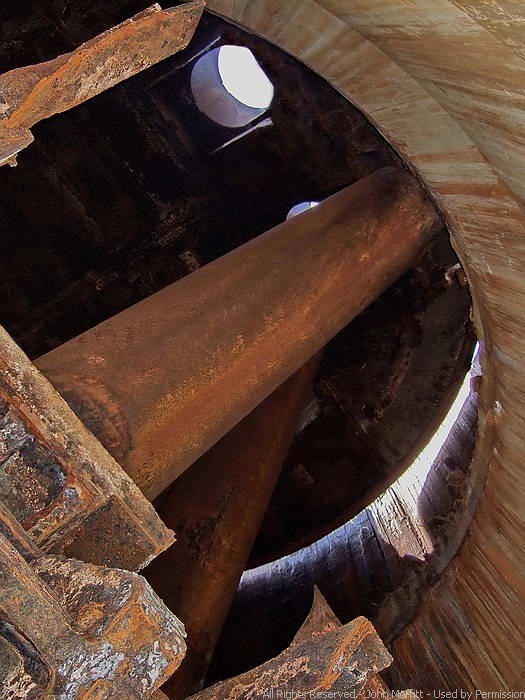 Battery Wilson - In the foreground are tons of loose metal and just behind it is the 14 inch barrel that is resting on the floor. The second barrel which protrudes its gun port is at the rear. The circular rotating portion of the turret with the gun ports can be clearly seen.